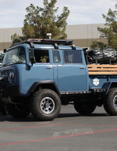 Side view of military-style blue forward-control FC-170 FC-150 Jeep at aFe Power Car and Cafe event in Corona California