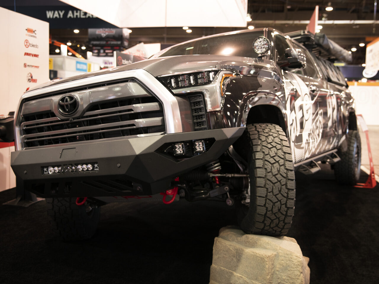 Grey 2022 Tundra driving over rock with overlanding setup at aFe POWER booth