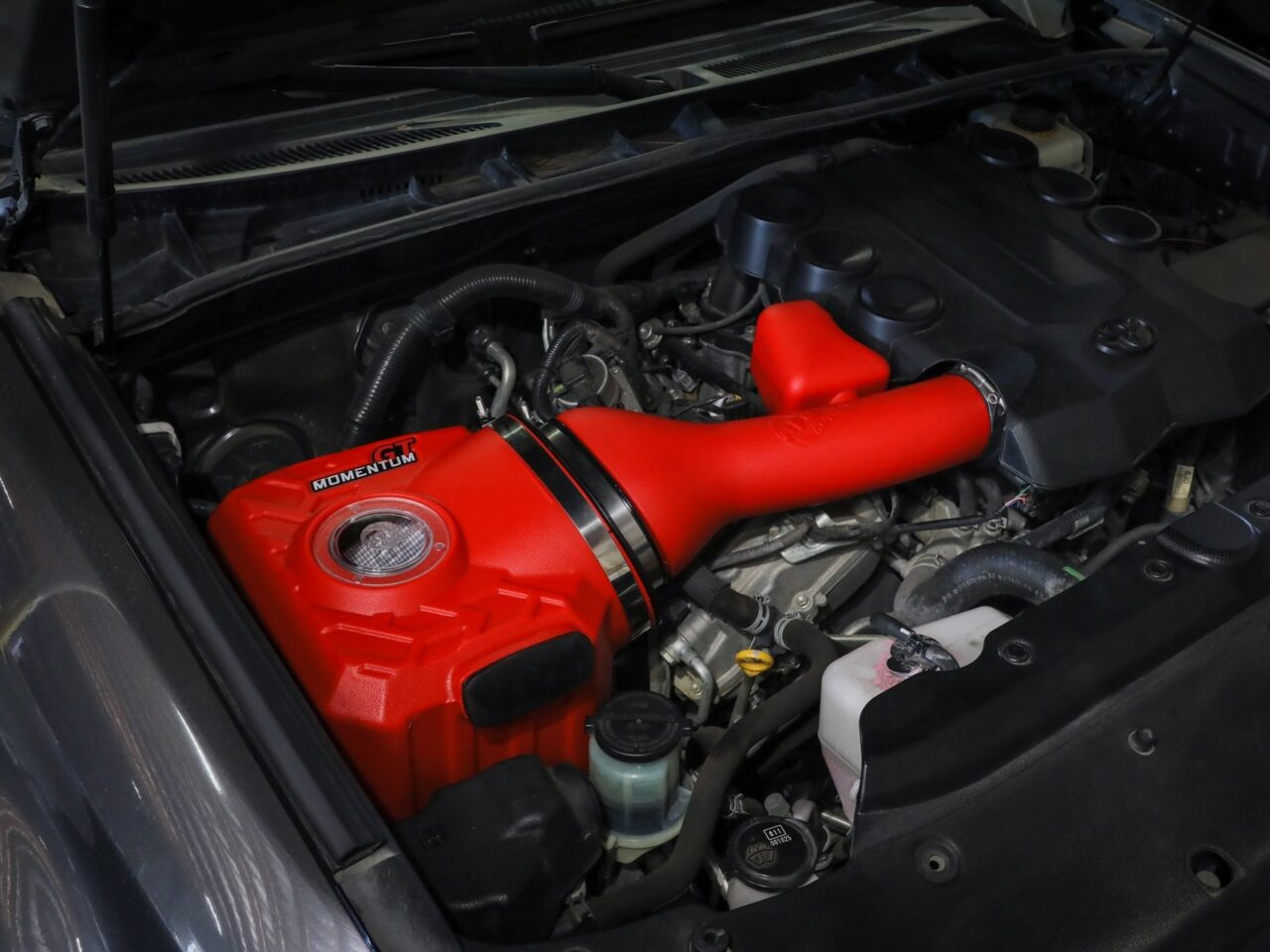Bright red aftermarket aFe POWER intake with tire tread design and clear sight window installed on 2022 Toyota 4Runner engine 