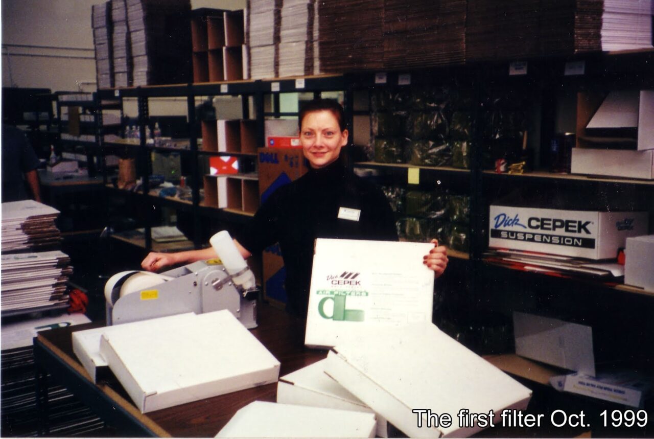 aFe owner woman holding first private labeled air filter box labeled Dick Cepek in front of filter manufacturing warehouse in 1999