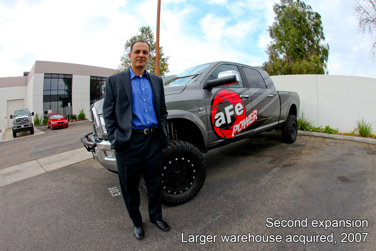 aFe Founder Nick Niakan in front of grey aFe POWER Ford F250 Truck with fisheye angle in front of aFe POWER 232 Granite St manufacturing warehouse in Corona CA