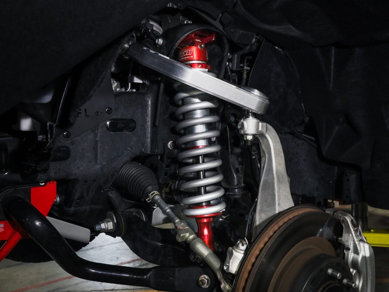 Closeup on aftermarket aluminum and zinc aFe POWER Sway-A-Way Coilover and Shocks with red accent installed on 2022 Toyota Tundra wheel well