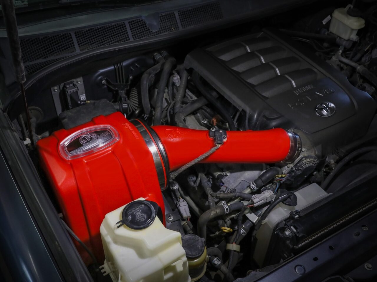 AFE aftermarket bright red rotational-molded heat-resistant plastic sealed cold air intake installed on engine of 2nd Gen V8 Toyota Tundra
