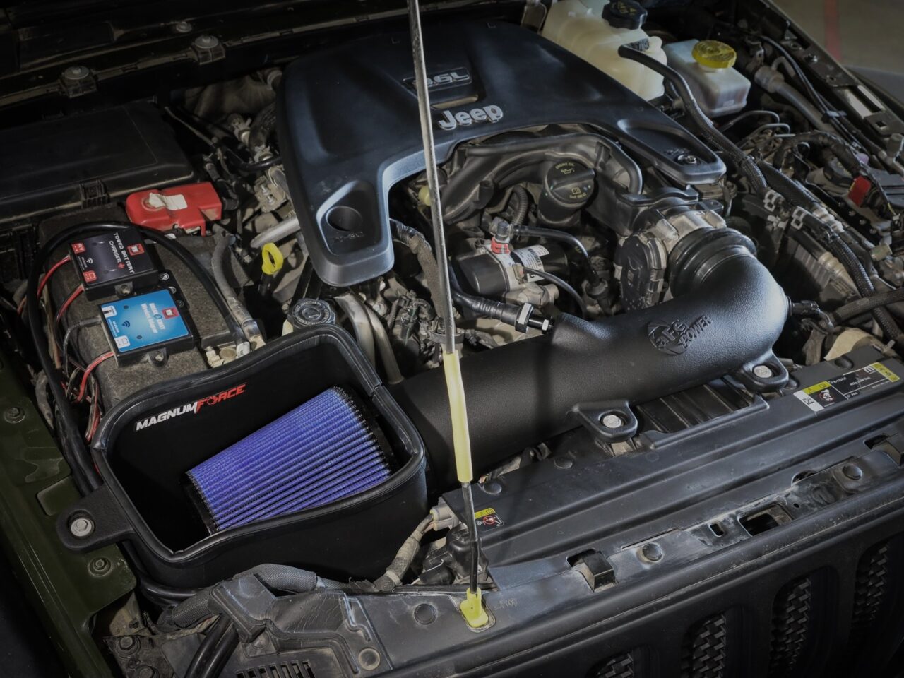 Aftermarket aFe open-style intake with huge open with huge blue oiled performance filter lack plastic airbox installed in engine under hood of 2022 Jeep Wrangler JL with V6-3.6L engine