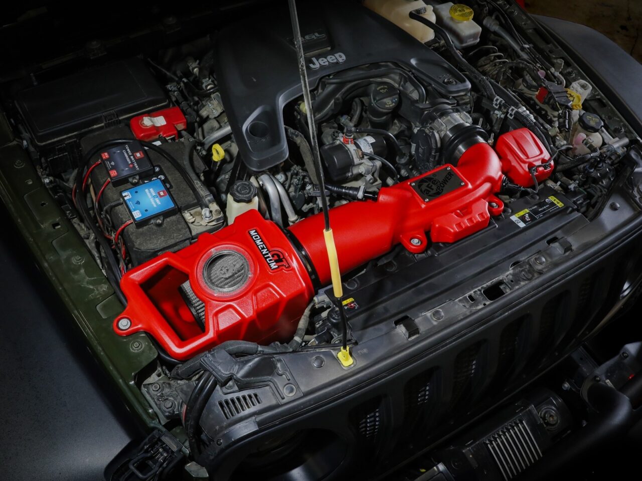 Bright red plastic sealed cold air intake with plastic window to grey dry filter installed on engine bay of V6 3.6L engine of Gladiator JT and Wrangler JL