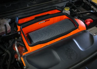 Orange open intake with massive large air filter with expanded metal installed in RAM TRX truck showing dinosaur easter egg in engine bay