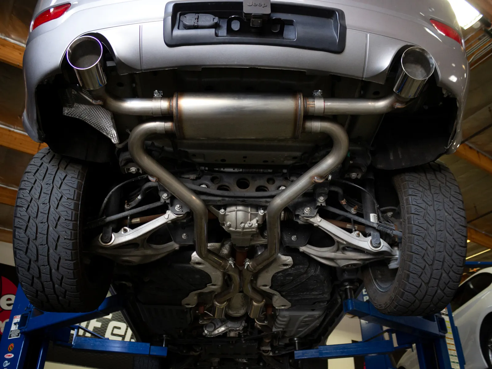 Under-vehicle view of aFe Cat-Back exhaust with dual tips installed on WK2 Grand Cherokee