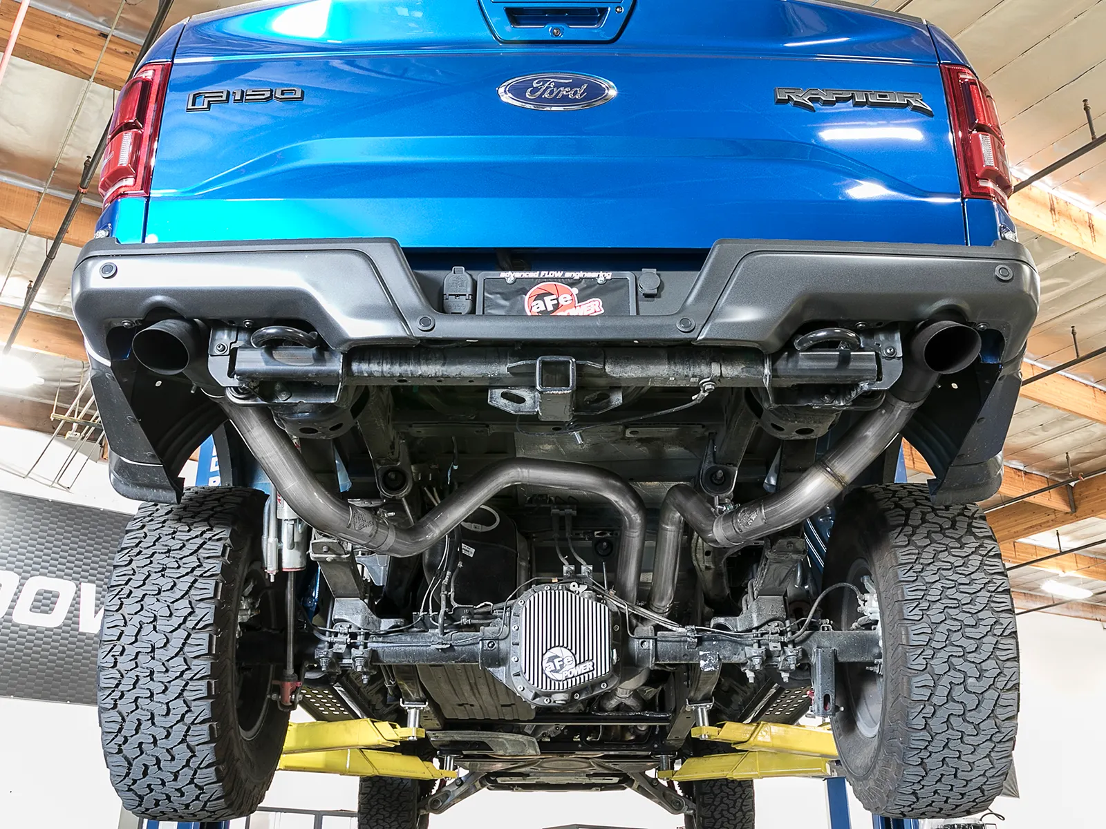 Blue Gen 2 F-150 Raptor on lift with aFe off-road exhaust and rear differential cover