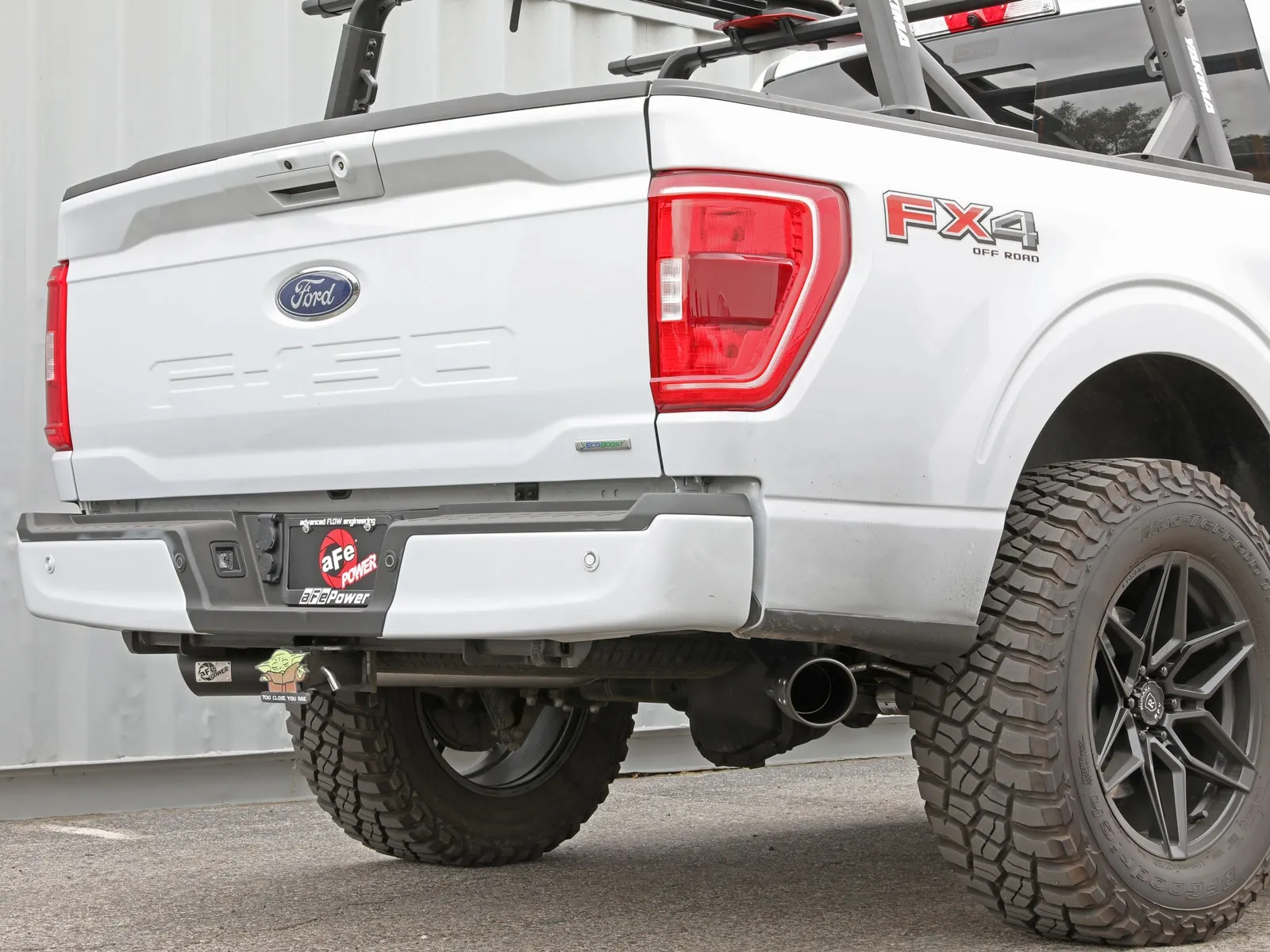 Rear angle of White Ford F-150 EcoBoost with aftermarket aFe exhaust tips pointed outwards behind the rear wheels