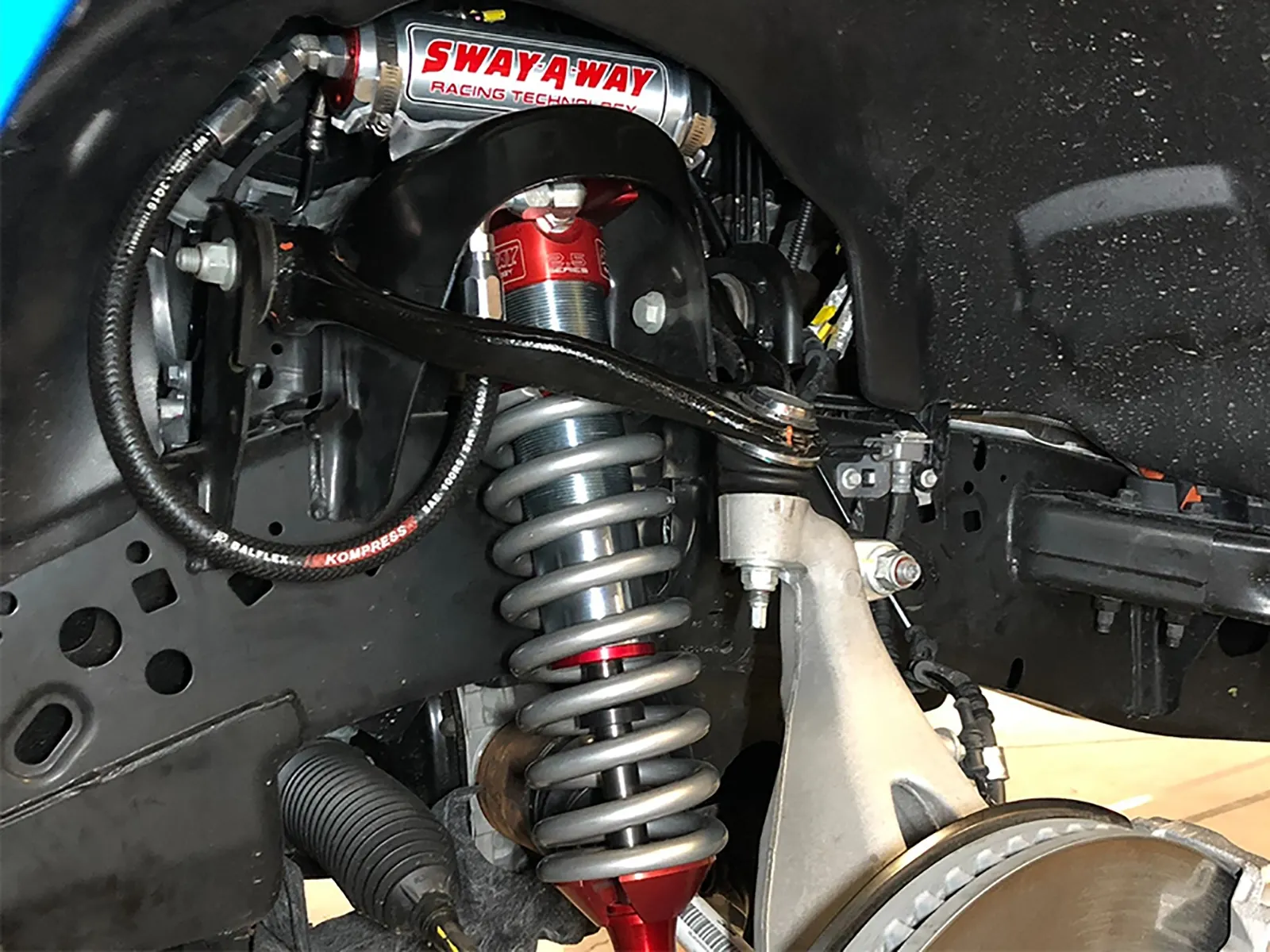 Red aluminized Sway-A-Way front coilover shocks for off-roading installed on Ford F-150 without wheels and tires
