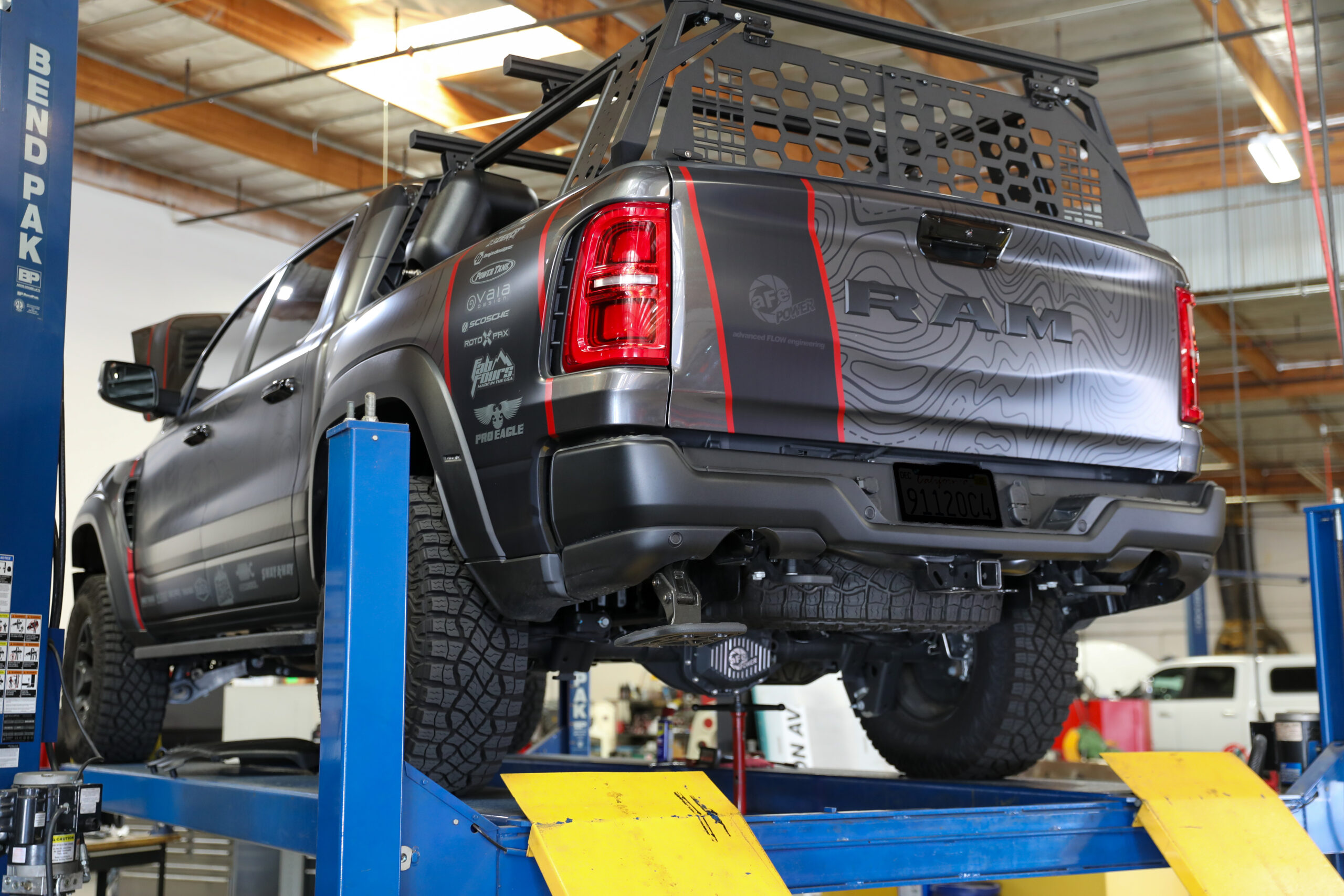 Rear view of grey Ram RHO with wrap with overland gear on trunk