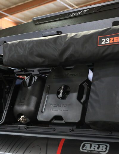 SEMA Build 2025 Ram 1500 RHO Build - 23 ZERO Armadillo Horizon 2 Rooftop Tent, 270° Awning, Rask Camping Shower, ROTOPAX Red 2-Gal Gas, Black 2-Gal Water, LEITNER Active Cargo System | Storage Boxes | Accessories