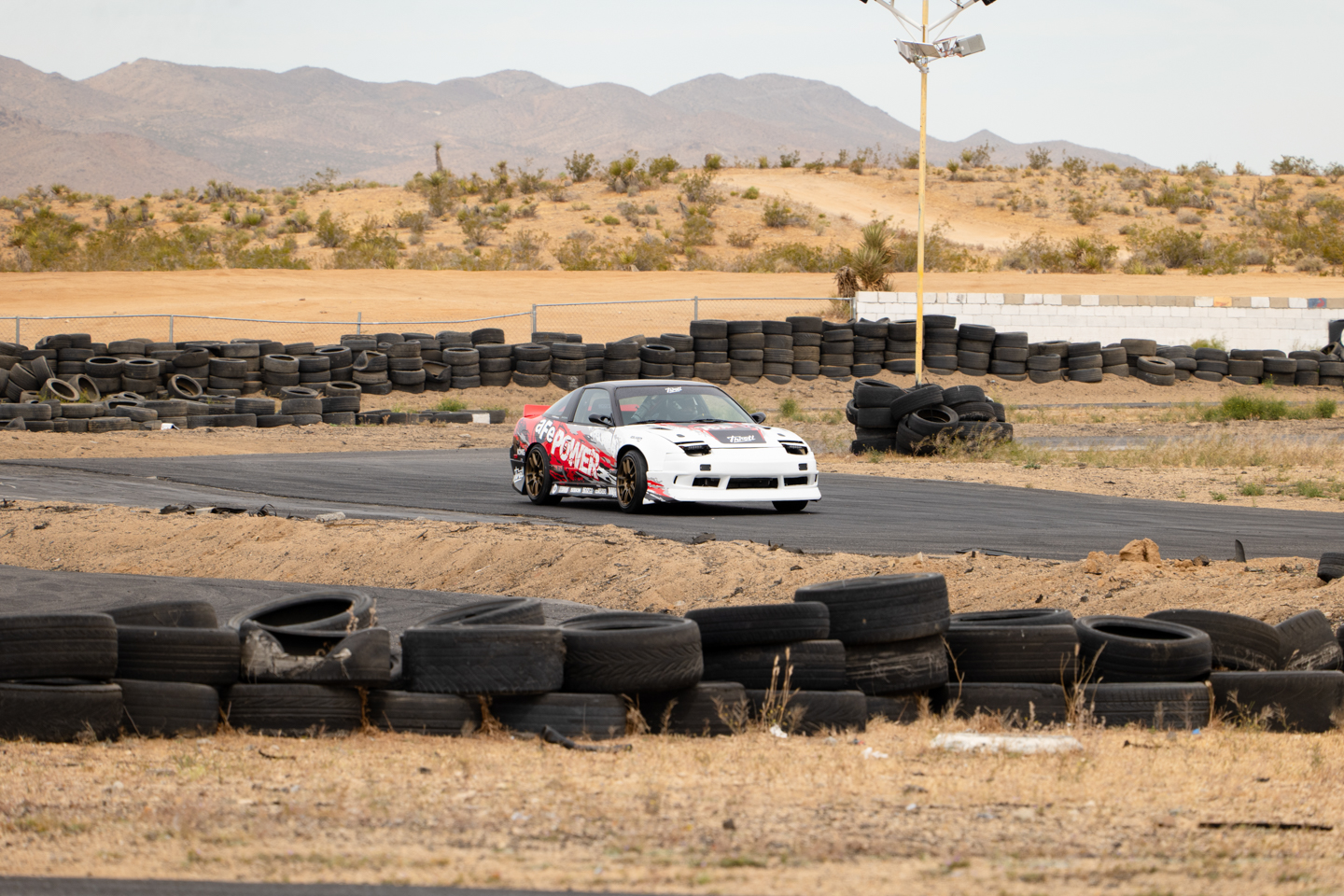 Nissan 240SX driving on Apple Valley Racetrack curve with tire barriers