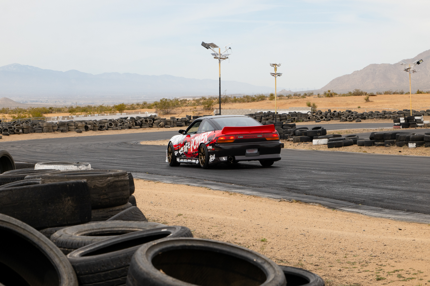 Rear of Nissan 240SX driving on Apple Valley Racetrack with tire barriers