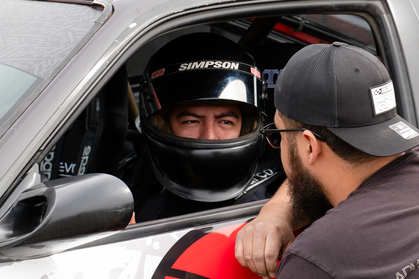 Luiz Perez in race helmet inside drift car talking to tech